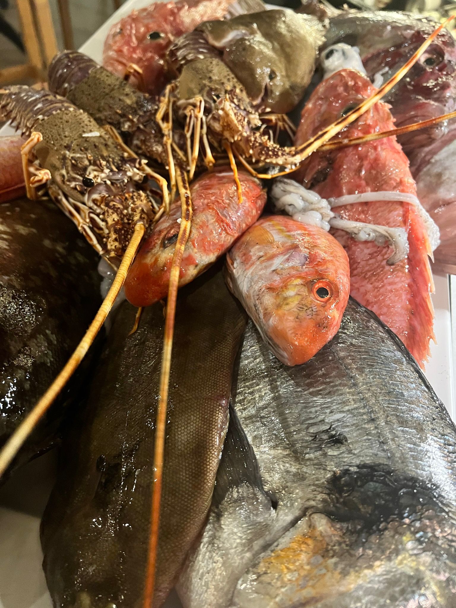 Torre di crudo di mare: aragosta, triglie e murena appena pescate, disposte su ghiaccio