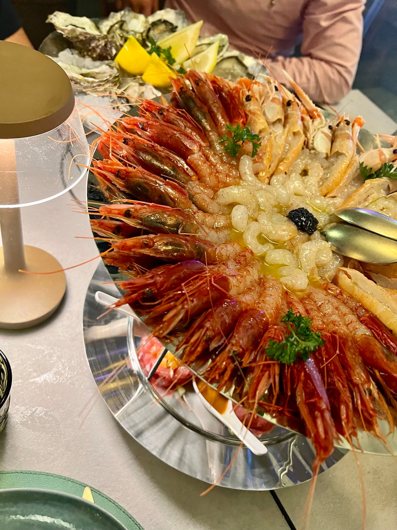 Tagliere di gamberi rossi crudi conditi con olio, pepe e caviale, servito in sala
